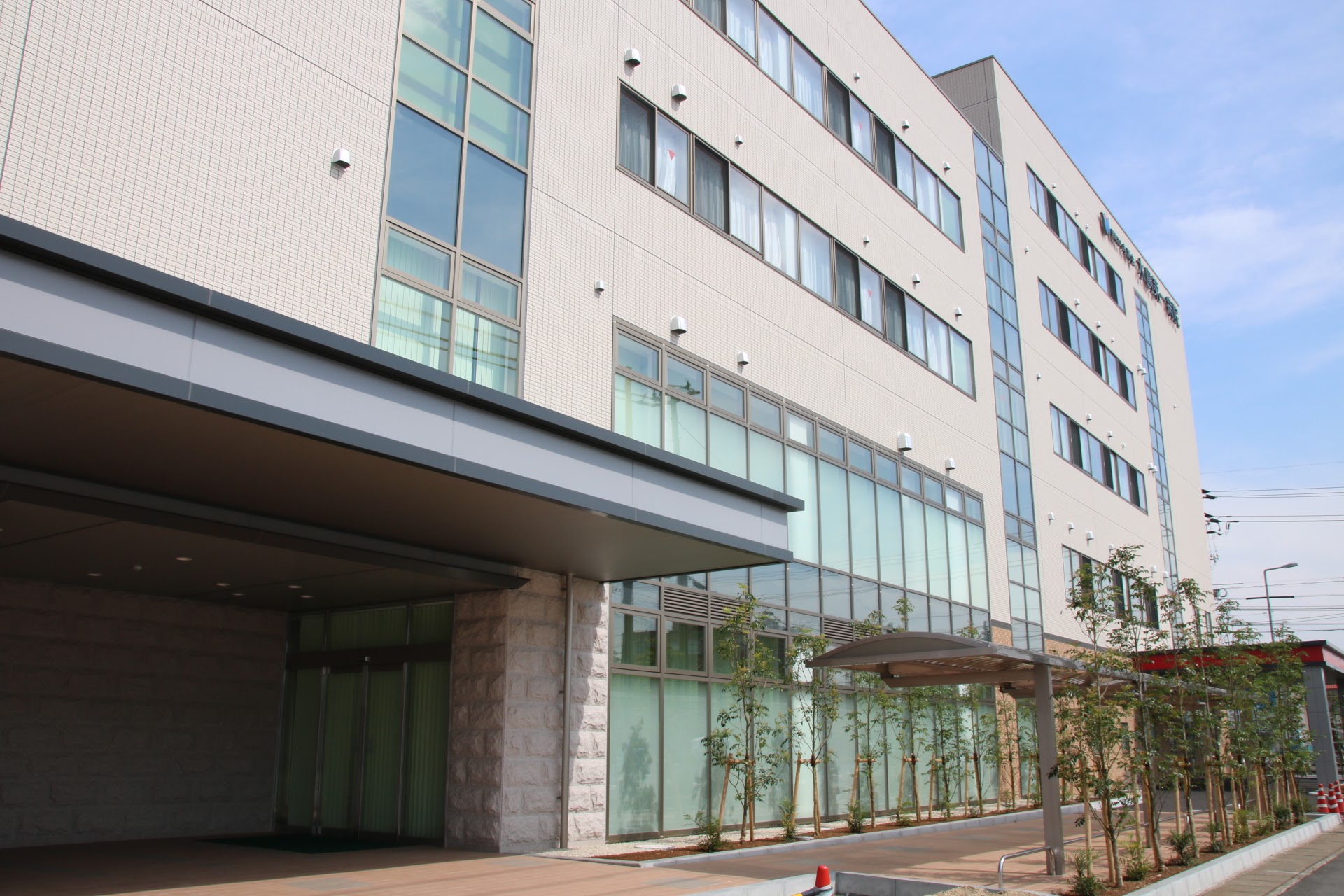 介護施設の建物外観。白基調の現代的な多層建築で、大型窓と エントランスが見える。